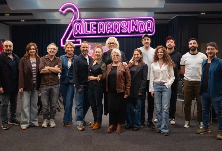 2 Aile Arasında film ekibi, yapımın adının yer aldığı ışıklı tabelanın önünde toplu halde poz veriyor.