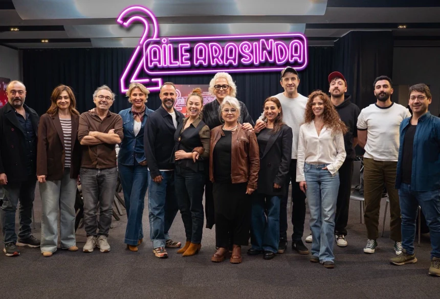 2 Aile Arasında film ekibi, yapımın adının yer aldığı ışıklı tabelanın önünde toplu halde poz veriyor.