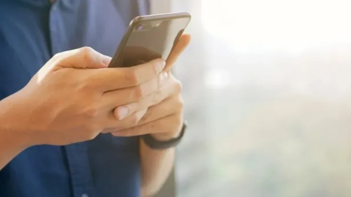 Akıllı telefonunu iki eliyle tutan kişi