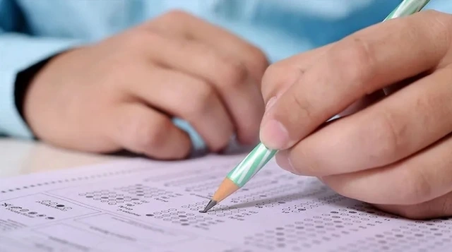 Bir kişinin sınav kâğıdındaki soruları kalemle işaretlemesi
