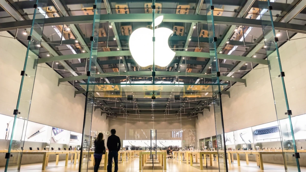 Cam cepheli bir Apple mağazasının girişinde ışıklı Apple logosu
