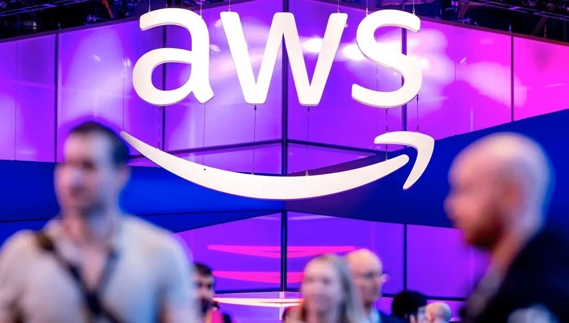 AWS logosunun önünde fuar alanında bulunan kişiler