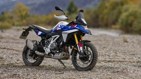 Mavi, beyaz ve kırmızı renkli BMW F 450 GS motosikleti taşlı bir zeminde duruyor