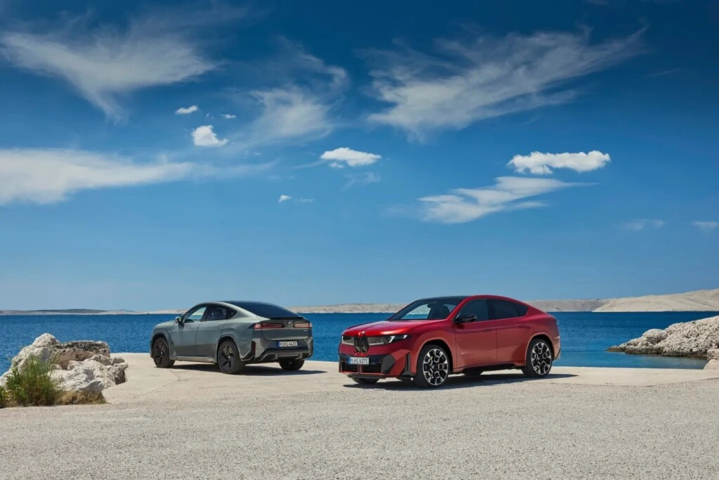 BMW iX4 modelleri sahil kıyısında yan yana park etmiş halde