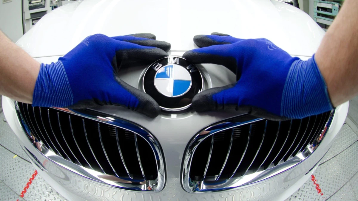 Mavi eldivenli ellerin BMW logosunun bulunduğu otomobil ön ızgarasına yerleştirilmesi