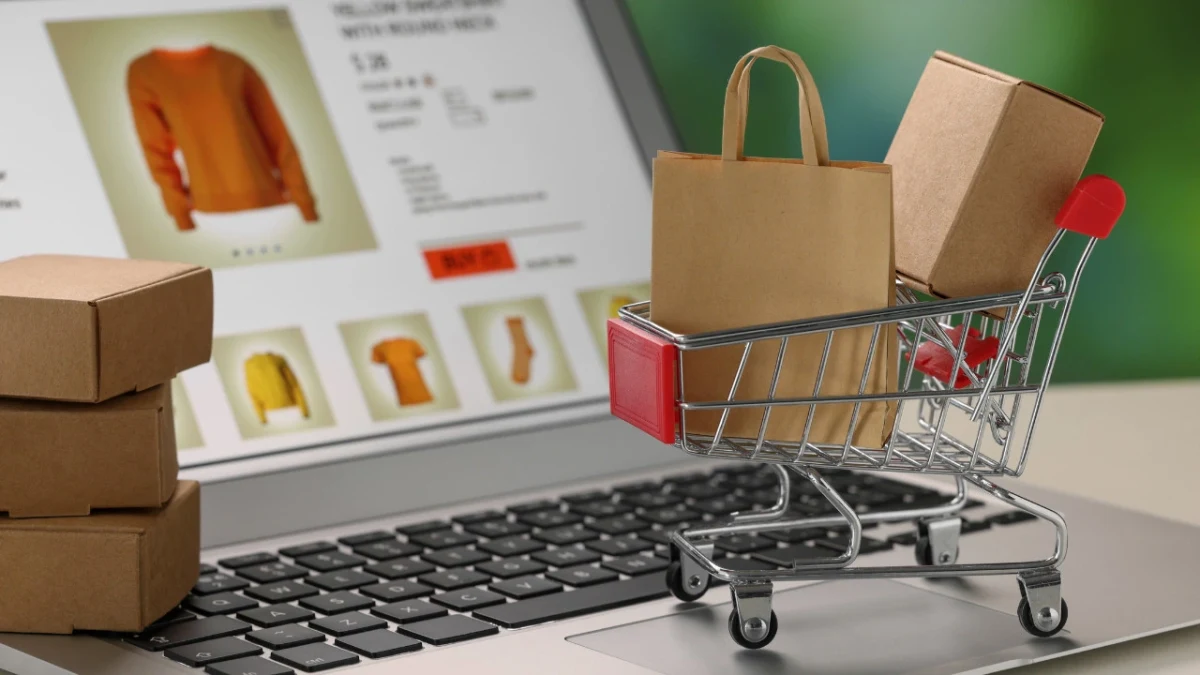 Dizüstü bilgisayardaki çevrim içi ürün sayfasının önünde alışveriş sepeti ve paketler