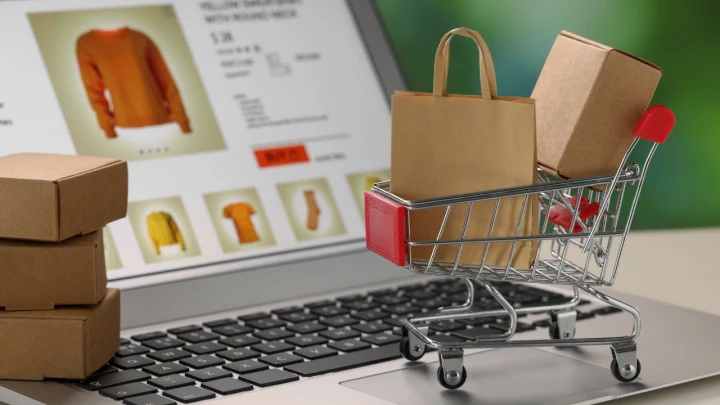 Dizüstü bilgisayardaki çevrim içi ürün sayfasının önünde alışveriş sepeti ve paketler