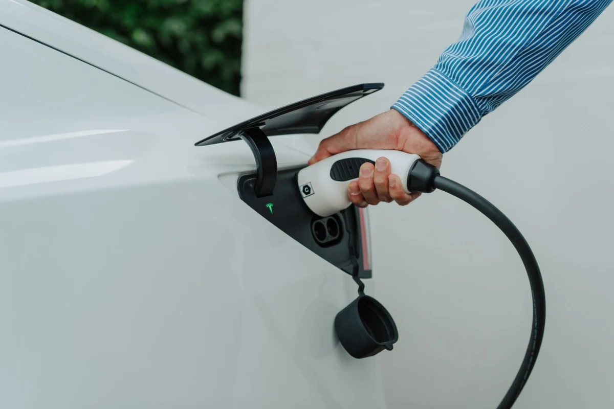 Elektrikli otomobilin şarj girişine kablo takan kişi