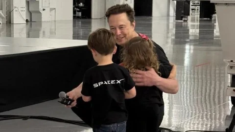 Elon Musk, SpaceX logolu tişört giyen iki çocukla birlikte