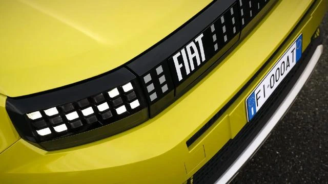 Sarı renkli bir Fiat otomobilin ön bölümünde marka logosu ve aydınlatmalı ızgara detayı