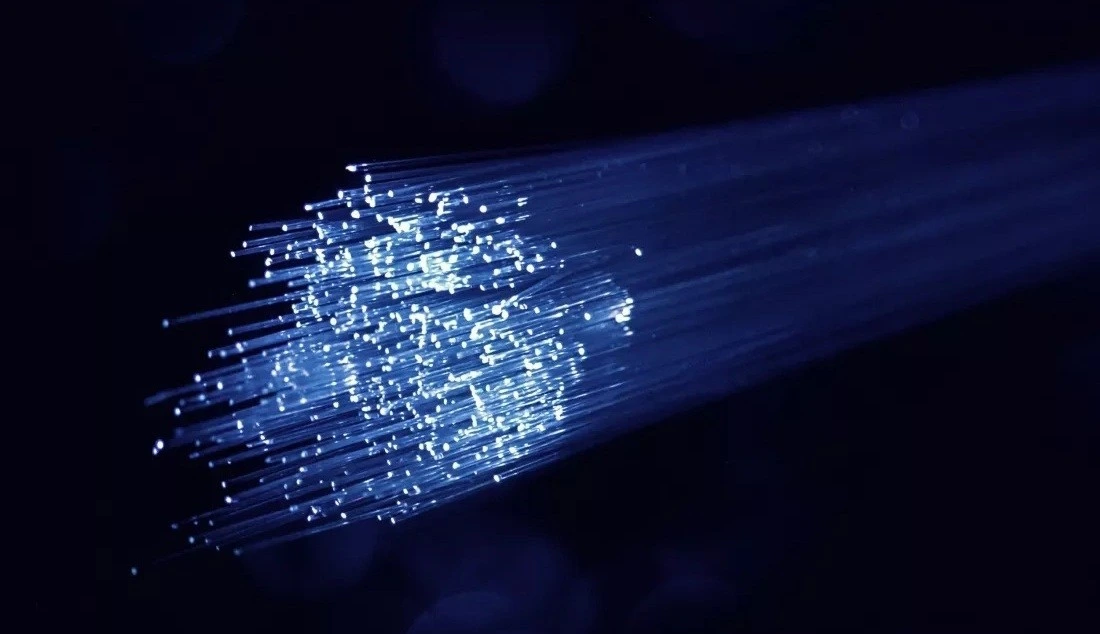 Karanlık arka planda ışık saçan fiber optik lifler