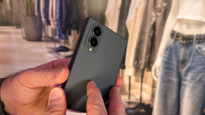Bir kişinin elinde tuttuğu koyu renkli, arka kameraları görünen katlanabilir Samsung telefon