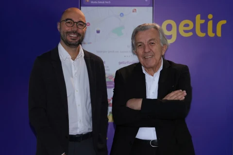 Getir logosu önünde yan yana duran iki erkek