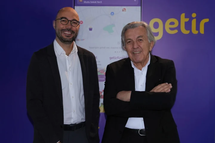 Getir logosu önünde yan yana duran iki erkek