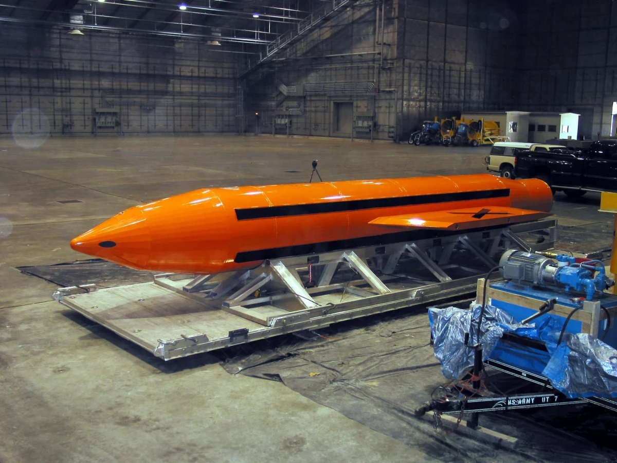 Turuncu renkli MOAB bombası bir hangarda taşıma sehpası üzerinde duruyor