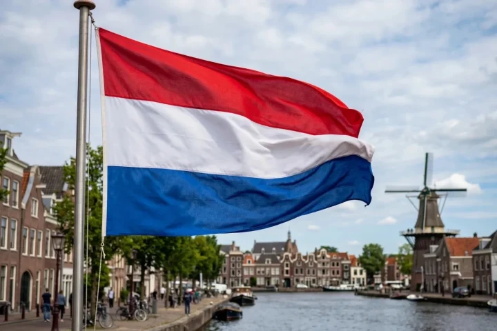 Hollanda bayrağı, kanal ve tarihi binaların önünde dalgalanıyor