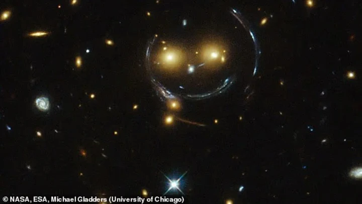 Hubble görüntüsünde iki parlak galaksi ve kavisli ışık izleri, karanlık uzay fonunda gülümseyen bir yüzü andırıyor.