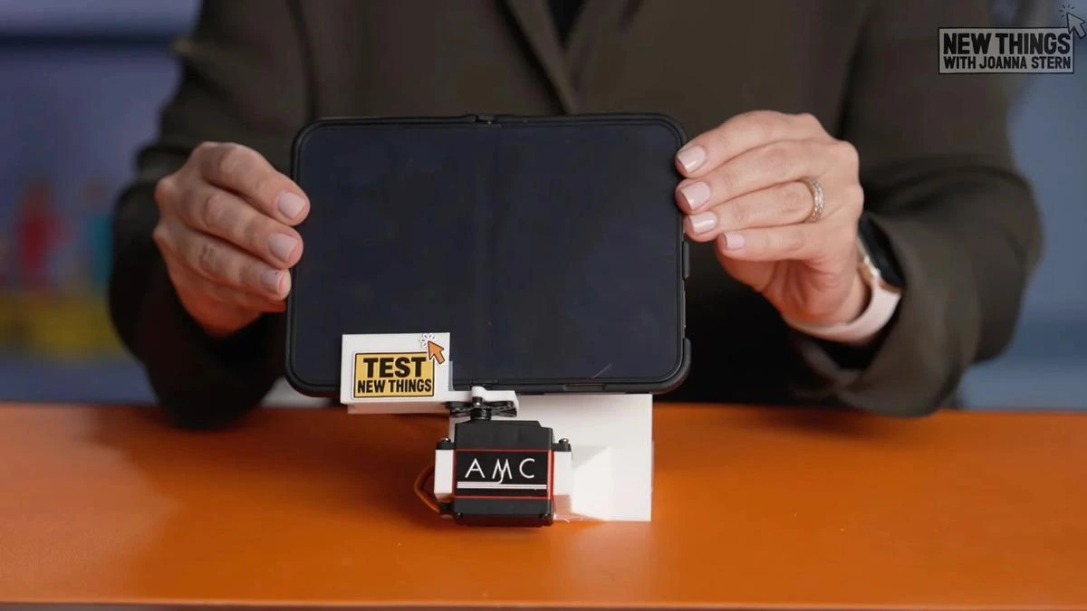 Bir kişi, mekanik test düzeneğine yerleştirilmiş açık katlanabilir telefonu tutuyor