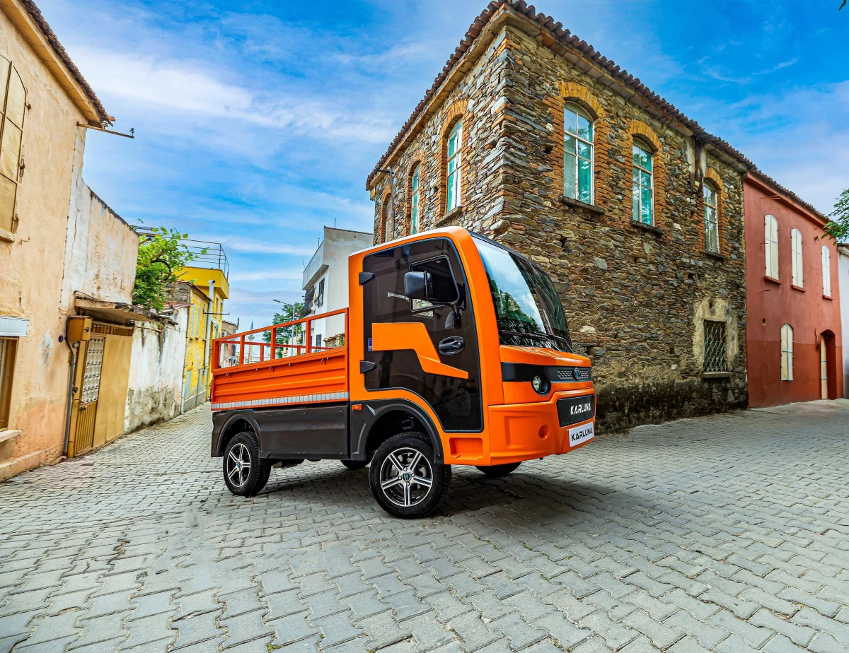 Arnavut kaldırımlı sokakta turuncu Karluna Pratik elektrikli araç