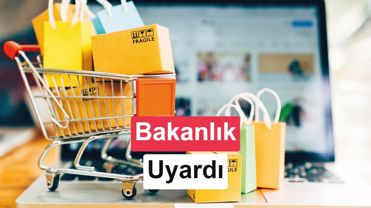 Bilgisayar ekranının önünde alışveriş sepeti ve renkli alışveriş çantaları