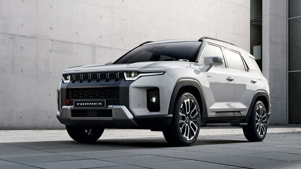 Açık renkli KGM Torres SUV, beton duvar önünde park hâlinde