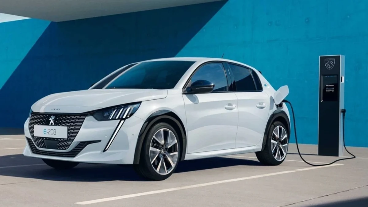 Beyaz Peugeot E-308 şarj istasyonunun yanında