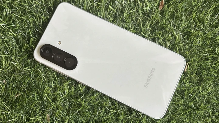 Çimlerin üzerinde arka yüzü görünen beyaz Samsung akıllı telefon