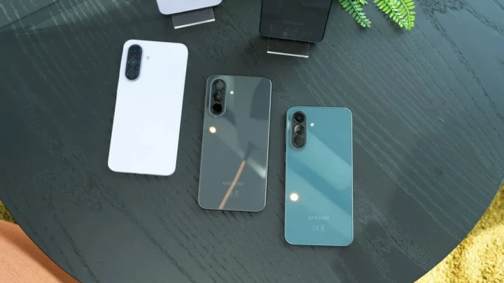 Koyu renkli bir masa üzerinde arka yüzleri görünen üç akıllı telefon