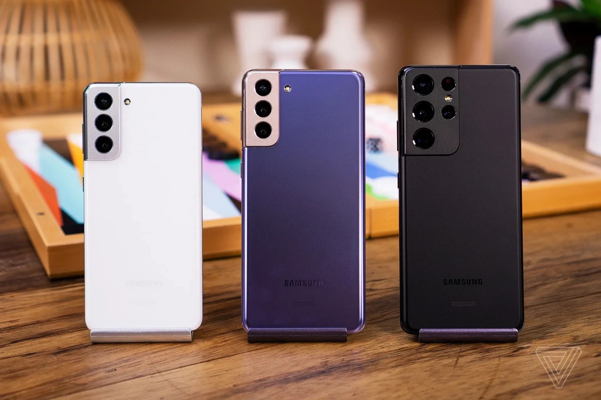 Ahşap masa üzerinde arkaları görünen beyaz, mor ve siyah Samsung Galaxy telefonlar