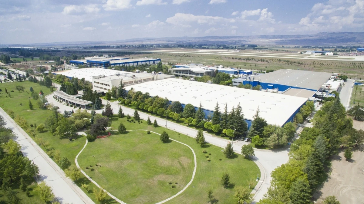 Ağaçlar ve yeşil alanlarla çevrili geniş bir sanayi tesisi kampüsünün havadan görünümü
