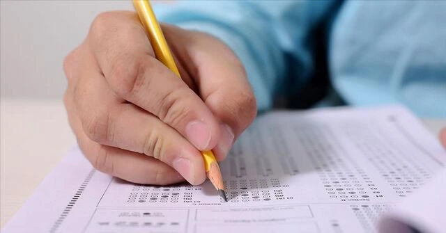 Bir kişi kurşun kalemle sınav cevap kâğıdındaki seçenekleri işaretliyor