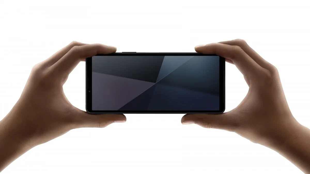 İki el tarafından yatay tutulan, ekranında geometrik desenler bulunan bir akıllı telefon