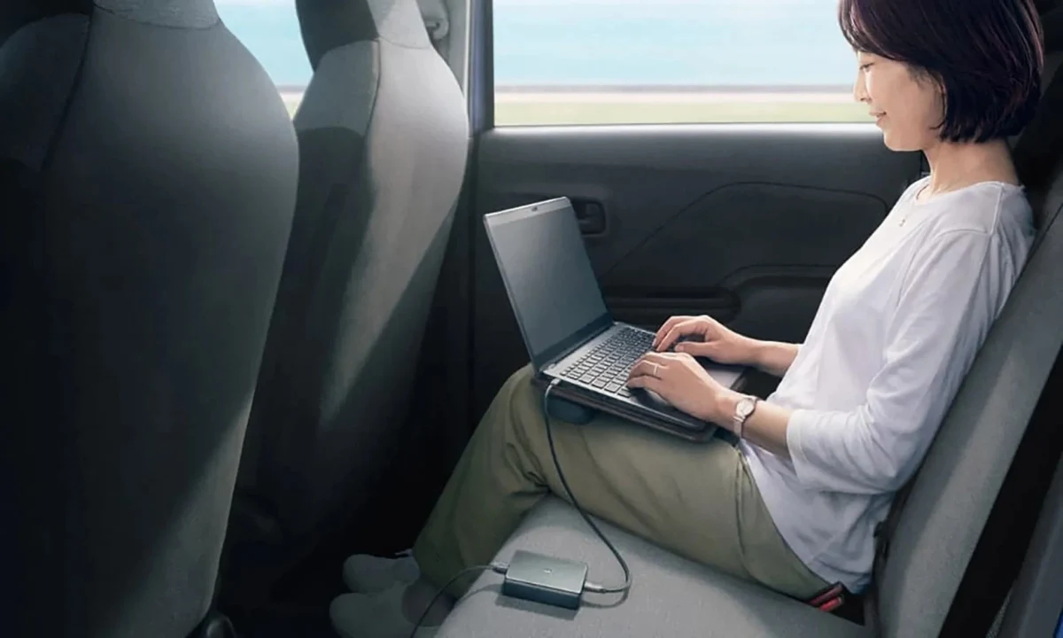 Suzuki e SKY arka koltuğunda dizüstü bilgisayar kullanan yolcu