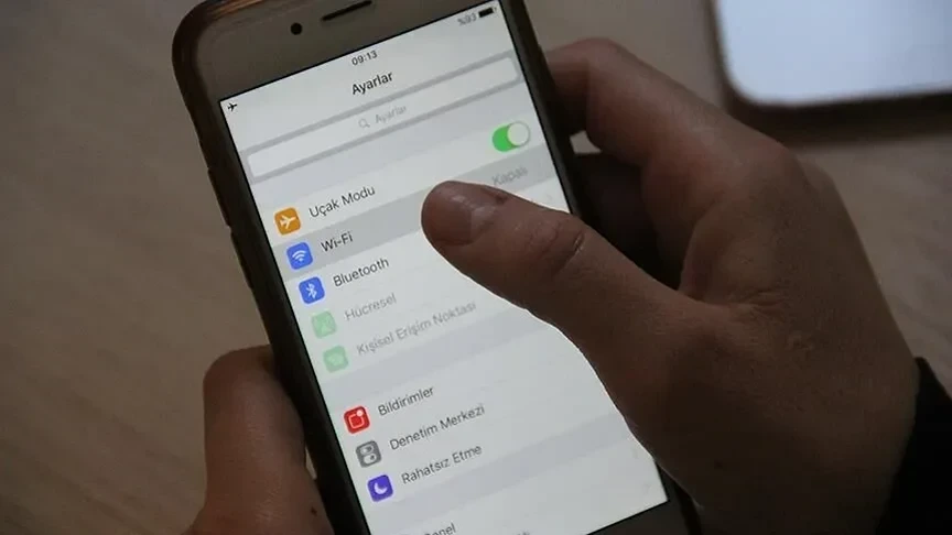 Bir kişi telefonun ayarlar ekranında uçak modu seçeneğine dokunuyor