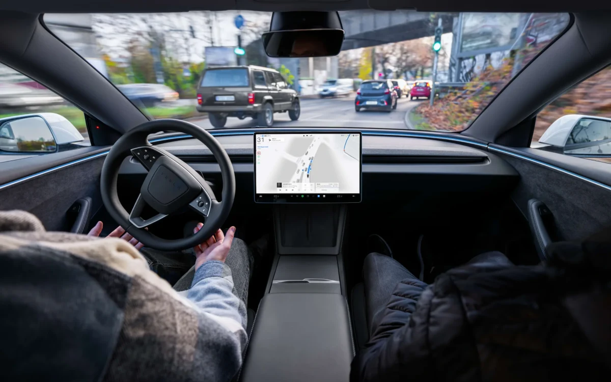 Tesla otomobilinin içinden görünen sürücü, direksiyon ve orta konsoldaki ekran
