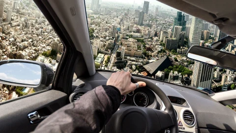 Otomobilin içinden görünen şehir manzarası ve direksiyon başındaki sürücü