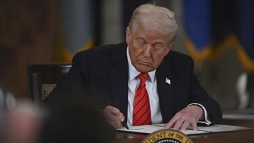 Donald Trump, masada bir belgeyi imzalarken görülüyor