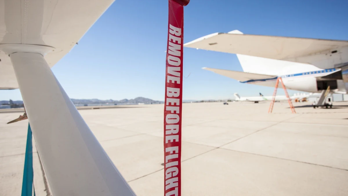 Uçak gövdesinden sarkan kırmızı “Remove Before Flight” şeridi