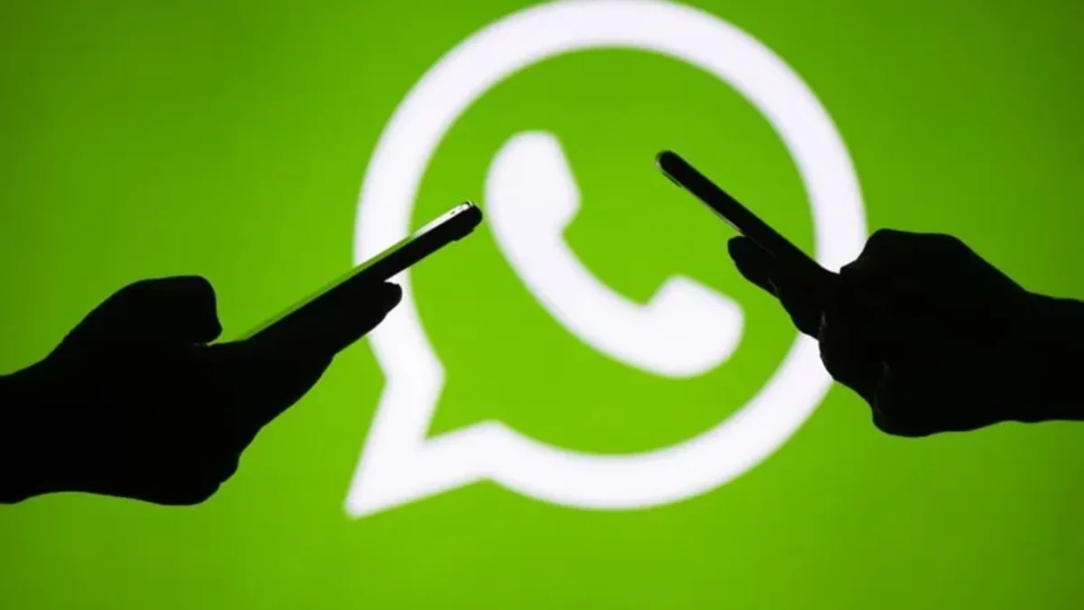 WhatsApp logosu önünde telefon tutan iki kişinin silüeti