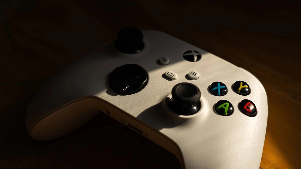 Ahşap yüzey üzerinde duran beyaz Xbox oyun kumandası