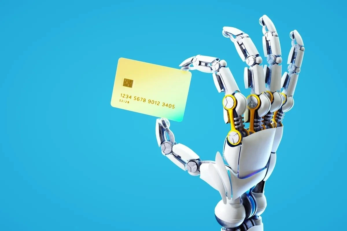 Banka kartı tutan robot eli, yapay zeka ajanlarının finansal hesaplara erişimini simgeliyor