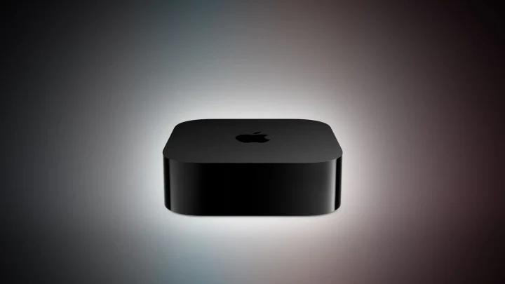 Koyu renkli Apple TV cihazı, karanlık arka plan önünde görüntüleniyor