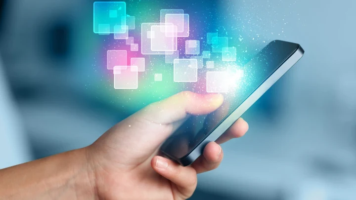 Bir kişinin elinde tuttuğu akıllı telefon ve ekran çevresinde görünen renkli kare grafikler